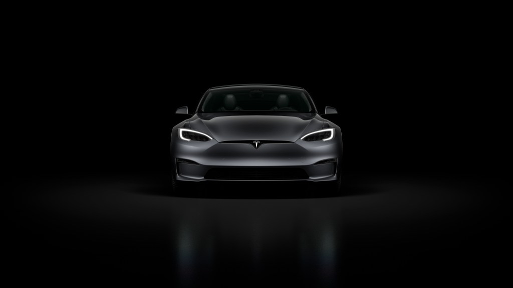 A black Tesla Model S Plaid in a black room
