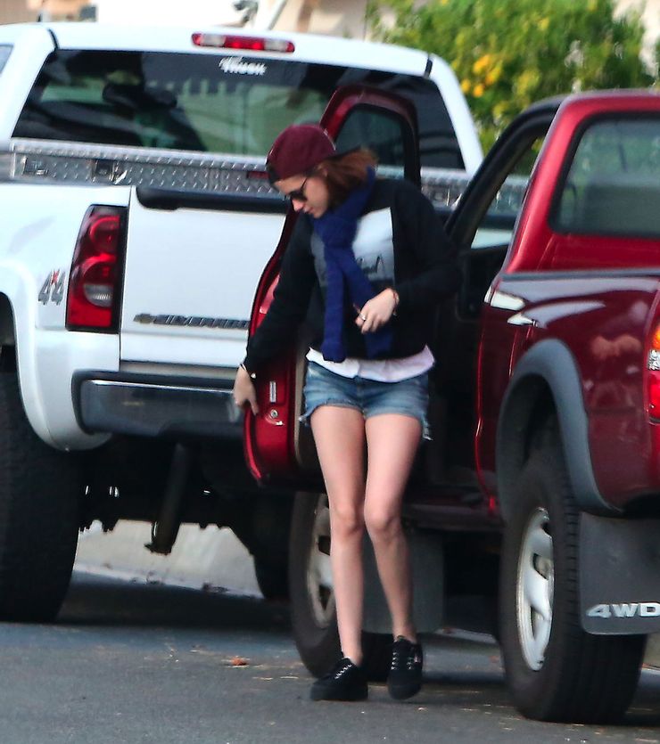 Kristen Stewart in glass and a backwards cap stepping out of a red Toyota Tacoma 