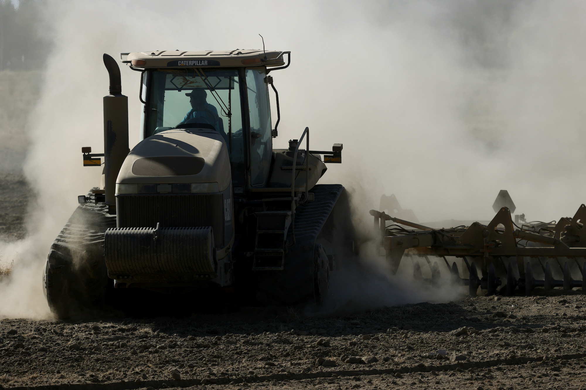 A tractor kicks up dust as it plows a dry field on May 26, 2021, in Chowchilla, California
