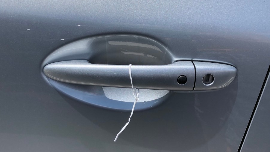 A white wire tied to a silver car door handle