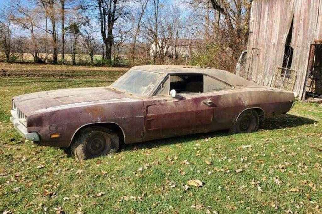 vintage dodge charger parked in the grass in need of some repairs