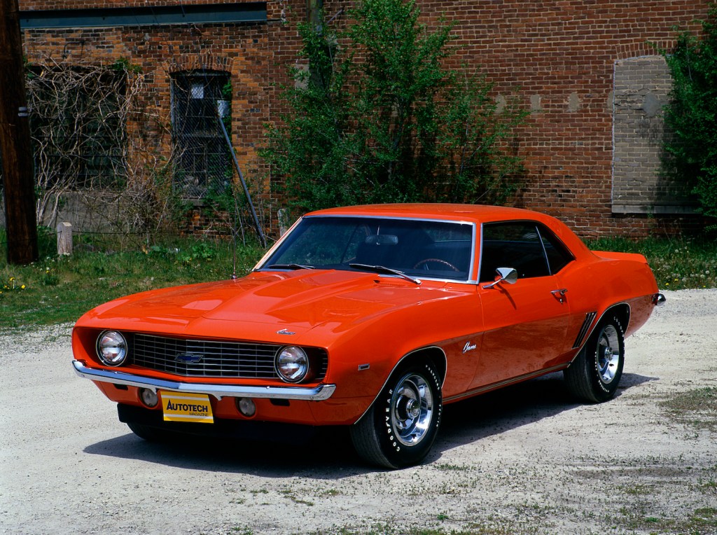 an orange 1969 Chevrolet Camaro Cop parked in front of a brick wall
