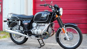 A black 1975 R90/6 in front of a red garage door