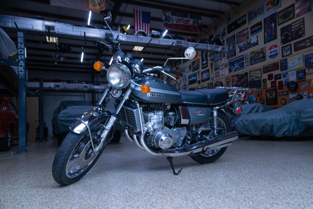 A gray-and-silver 1975 Suzuki GT750 in a garage with several covered cars