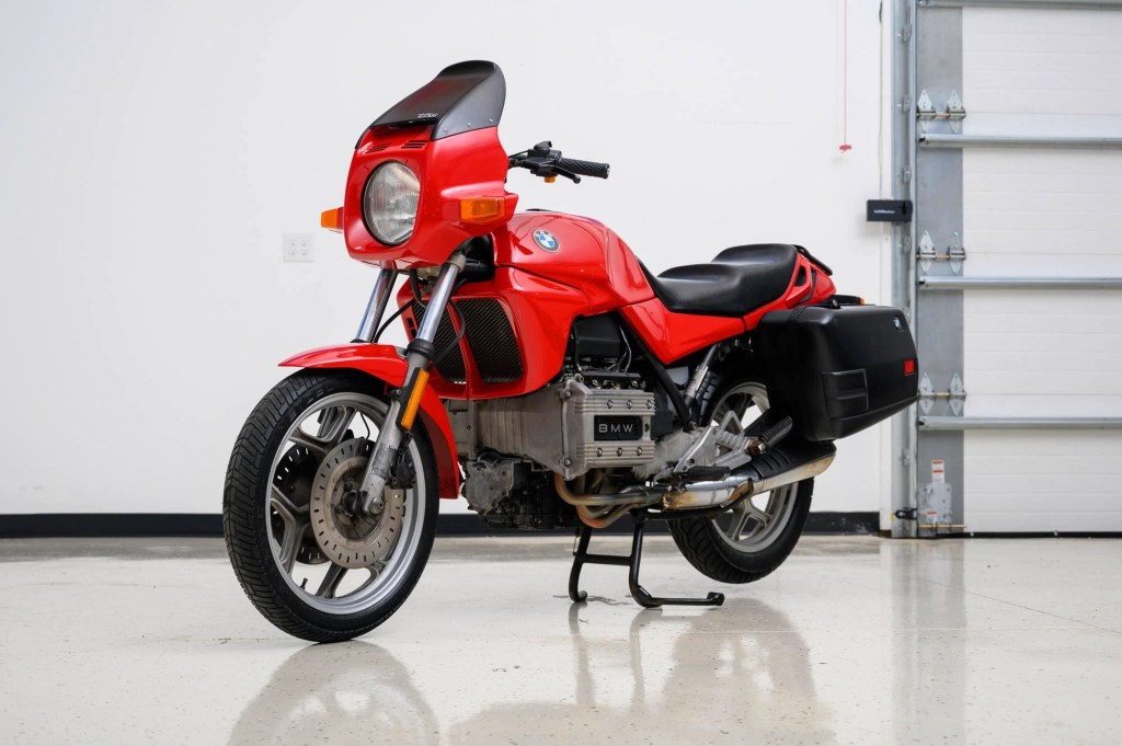 A red-and-black 1980 BMW K75 with black panniers in a garage