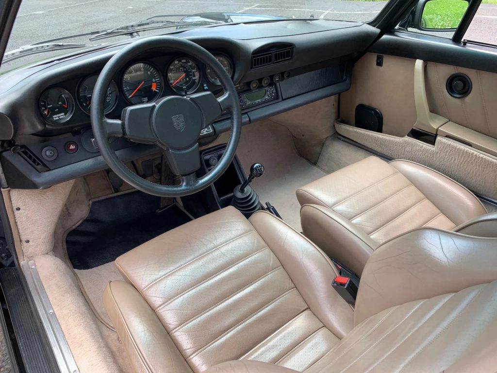 The black dashboard and beige-leather front seats of a 1984 Porsche 911 Carrera 3.2