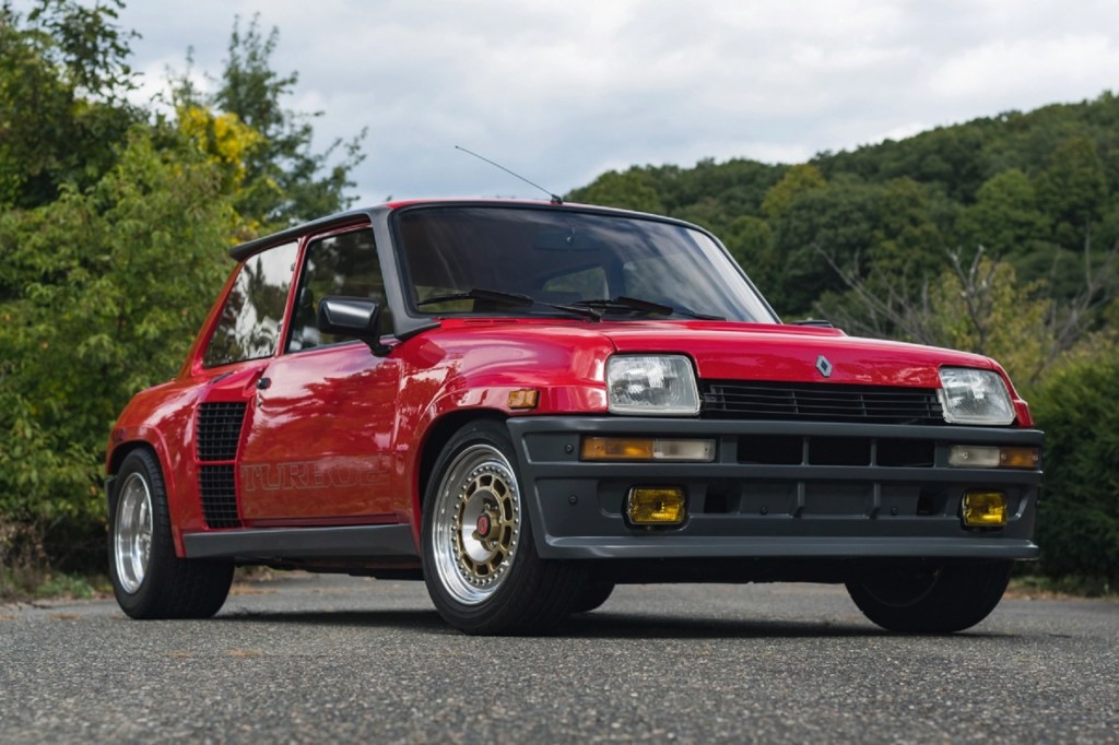A red-and-black 1985 Renault 5 Turbo 2 Type 8221 on a tree-lined road