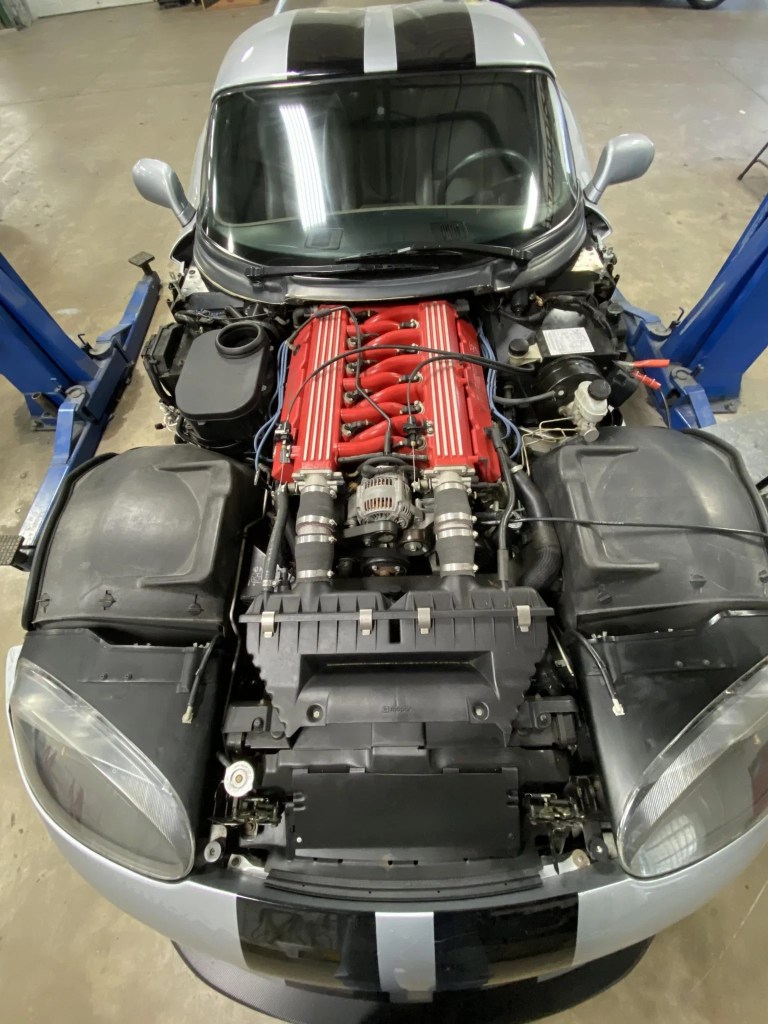 The open engine bay of a silver-with-black-stripes 1993 Dodge Hennessey Venom 600 RT/10 Aero