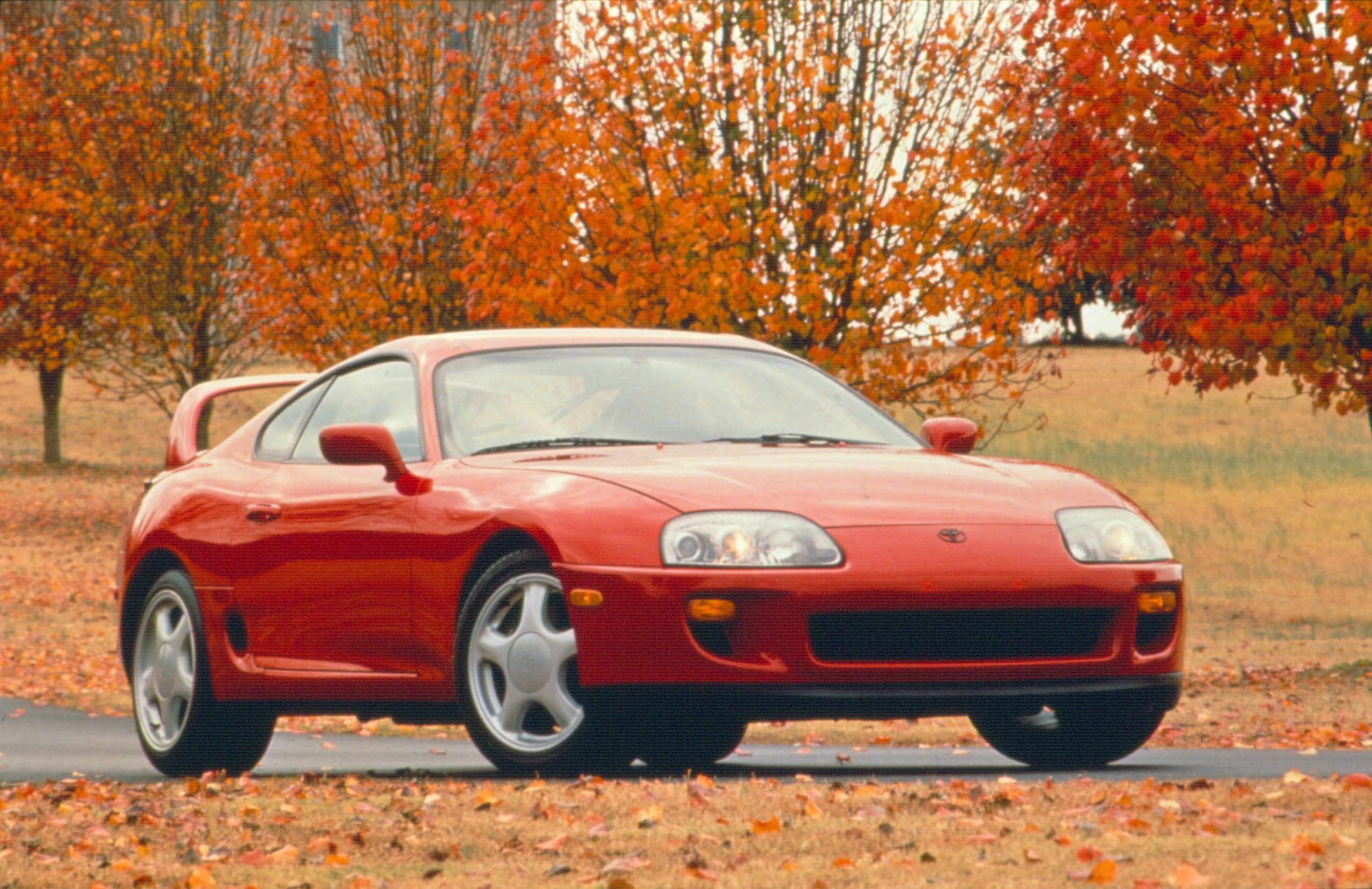 A red 1994 Toyota Supra among the fall leaves
