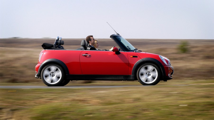 A red 2004 Mini Cooper convertible travels on a country road