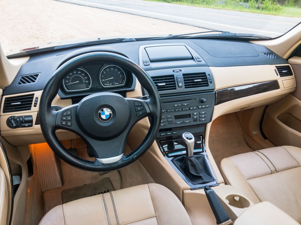 The tan-leather-upholstered front seats and ash-wood-trimmed tan-and-black dashboard of a 2008 BMW X3 3.0si