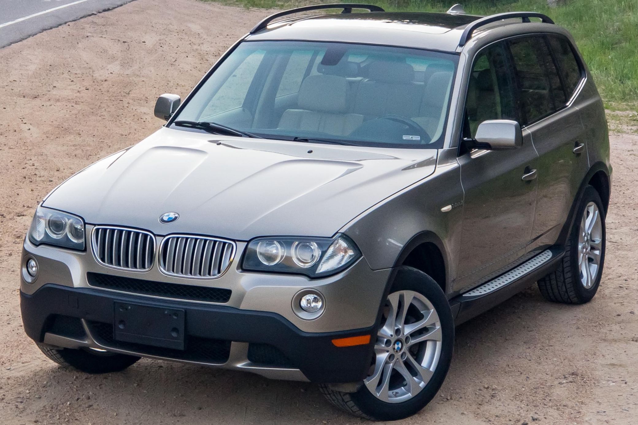 A tan 2008 BMW X3 3.0si parked by the side of the road