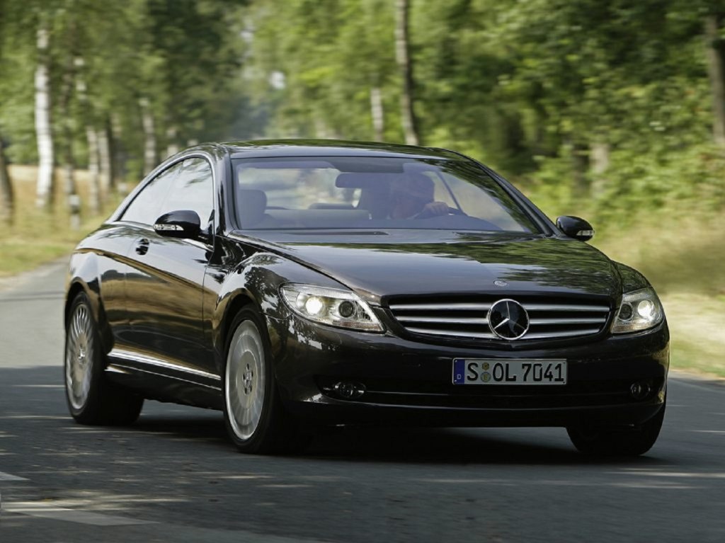 A black 2010 Mercedes-Benz CL550 4Matic driving down a tree-lined road