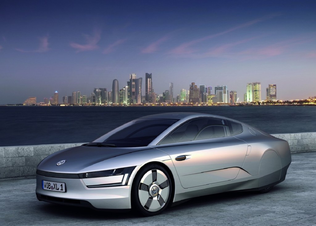 The silver 2011 Volkswagen XL1 Concept overlooking an oceanside city
