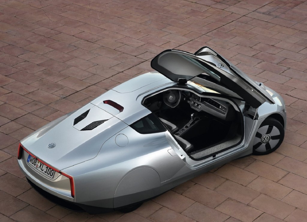 An overhead rear 3/4 view of a silver 2014 Volkswagen XL1 with its passenger-side door open