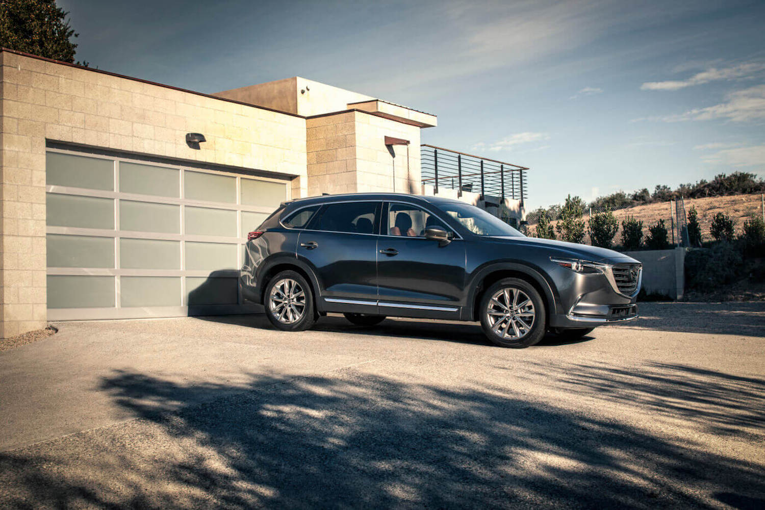 A dark grey 2018 Mazda CX-9 parked in a driveway, the 2018 Mazda CX-9 is one of the best CPO three-row SUVs under $30,000