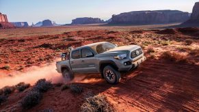 A dusty 2018 Toyota Tacoma flies up a dirt trail