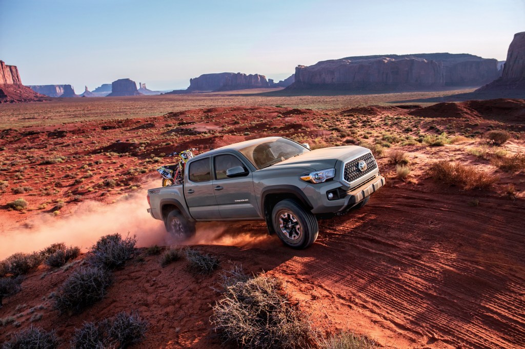 A dusty 2018 Toyota Tacoma flies up a dirt trail