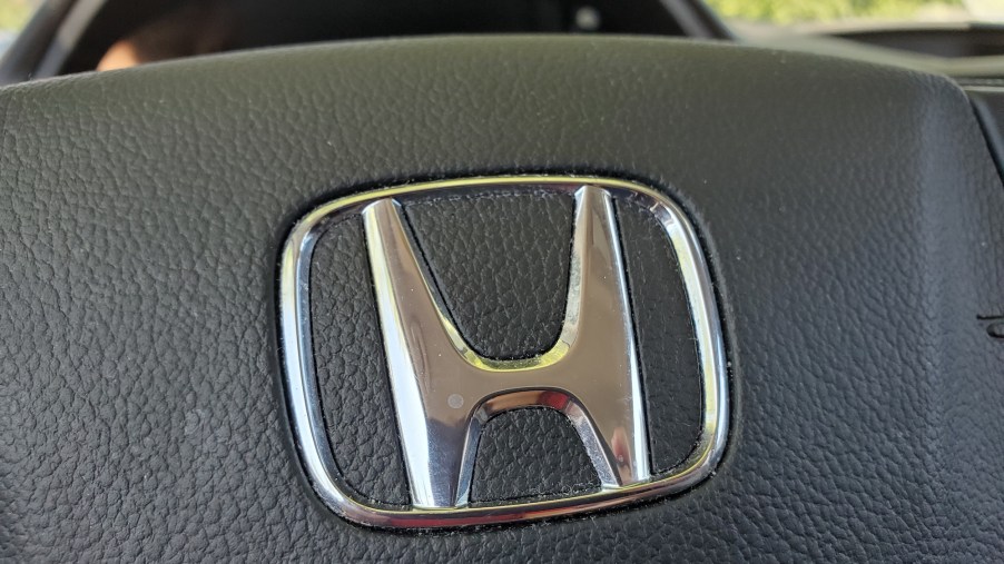 Close-up of a silver Honda logo on a black CR-V steering wheel