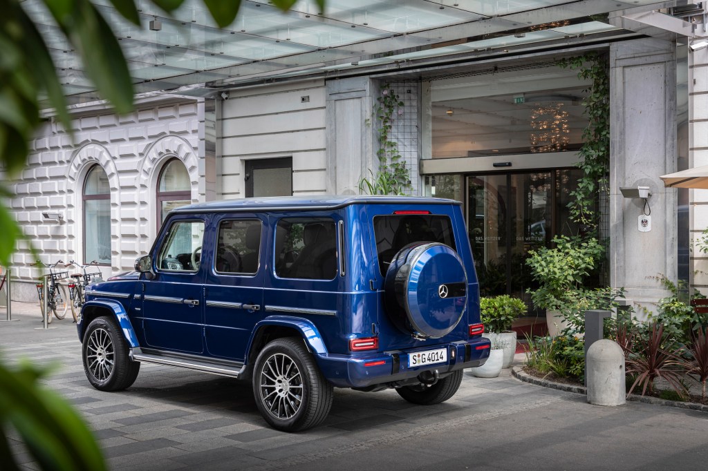 A blue 2019 Mercedes-Benz G-Class luxury SUV parked in front of a white building in Germany