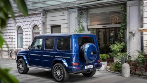 A blue 2019 Mercedes-Benz G-Class luxury SUV parked in front of a white building in Germany