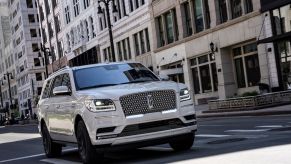 A white 2020 Lincoln Navigator luxury SUV model driving through an urban city environment