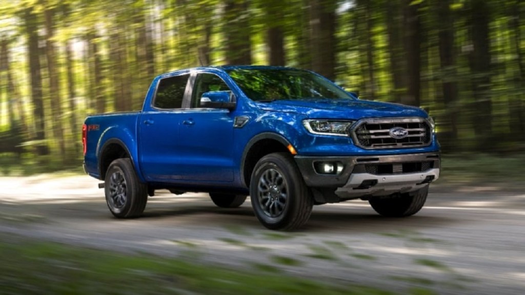 A blue 2020 Ford Ranger drives down a wooded road. 