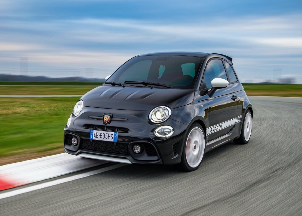 A black-and-white 2021 Abarth 695 EsseEsse goes around a racetrack corner at speed