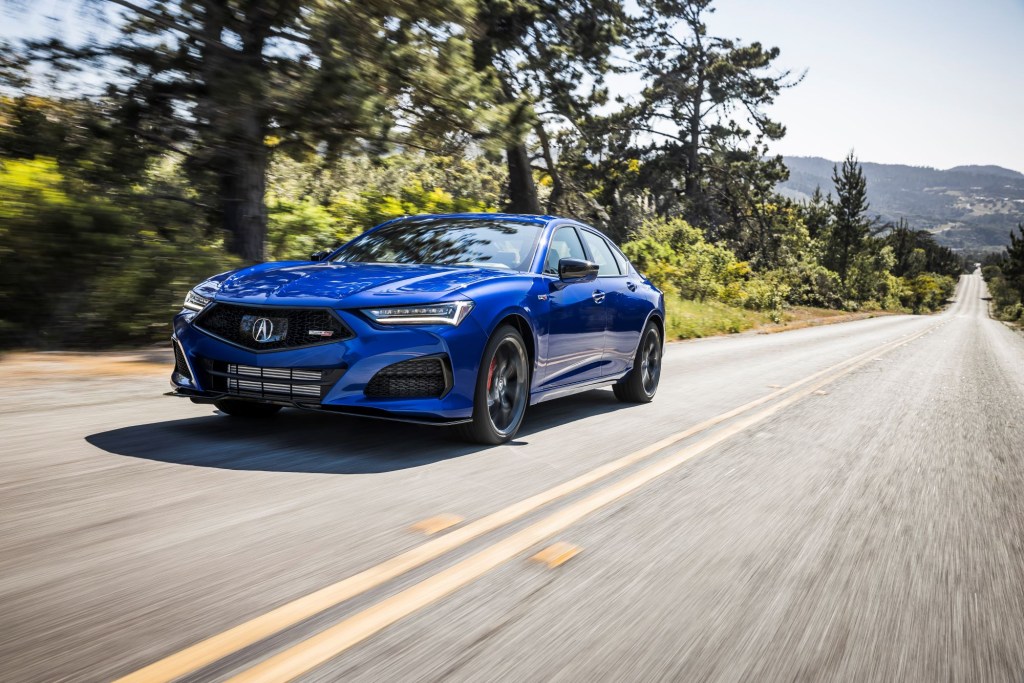 A blue 2021 Acura TLX Type S model driving down a forest highway