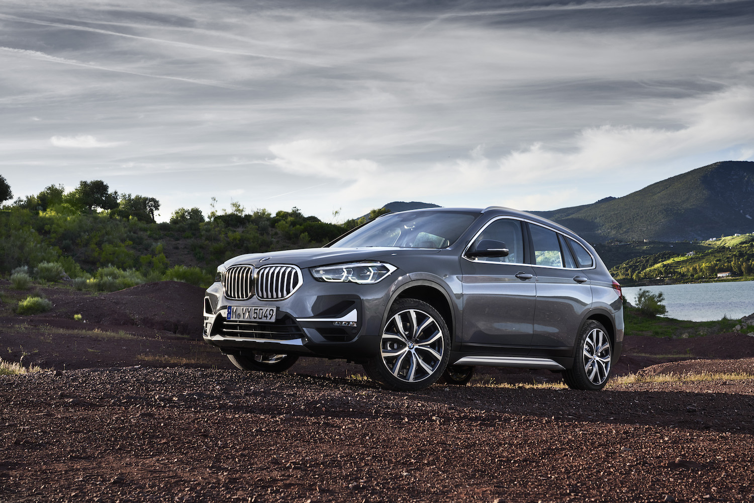 A grey 2021 BMW X1 driving up a hill, the 2021 BMW X1 is the cheapest new BMW SUV
