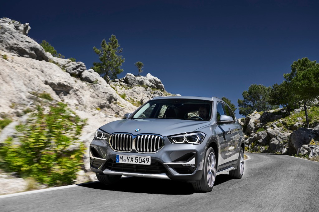 A grey 2021 BMW X1 driving around a corner, the 2021 BMW X1 is a new luxury SUV under $40,000