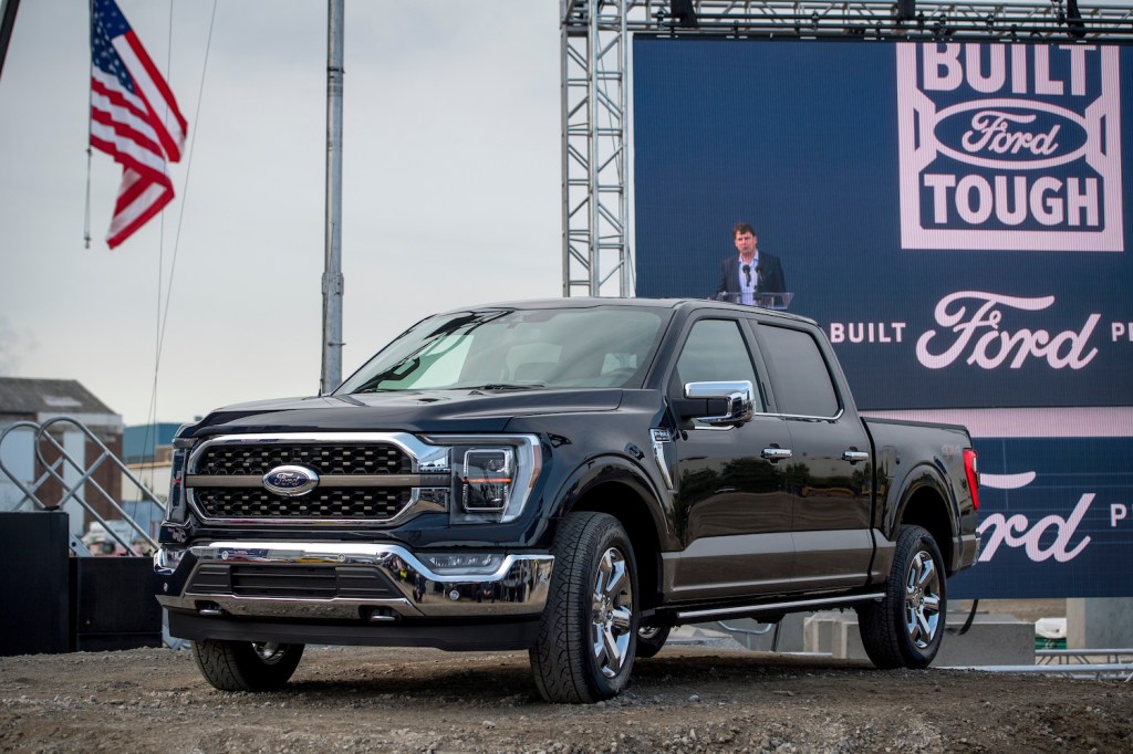 A Black 2021 Ford F-150 with an American flag and a billboard behind it, the Ford F-150 is among the best trucks of 2021