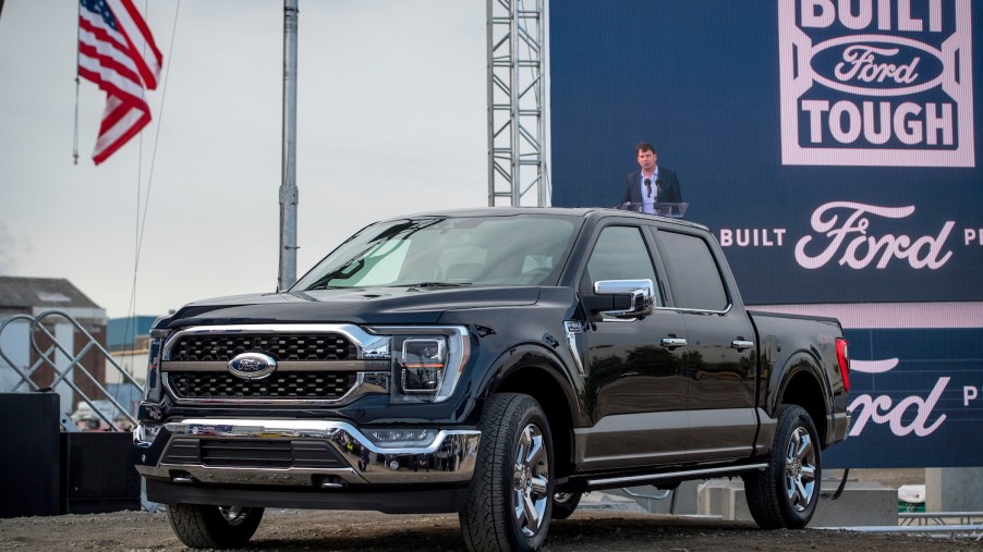A Black 2021 Ford F-150 with an American flag and a billboard behind it, the Ford F-150 is among the best trucks of 2021