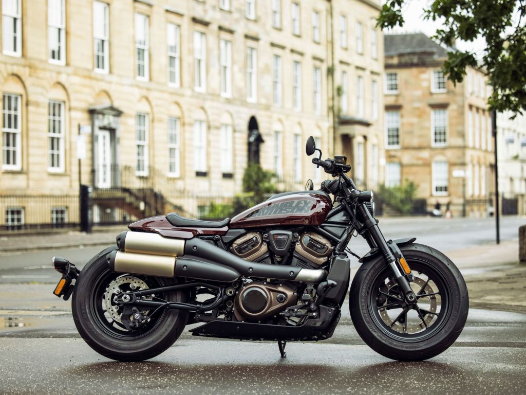 The side view of a maroon-and-black 2021 Harley-Davidson Sportster S in a European city