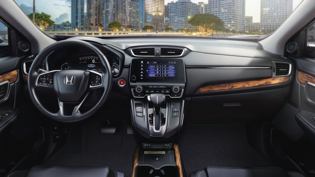 The black and woodgrain dashboard, center console, and steering wheel of a 2021 Honda CR-V Touring compact SUV