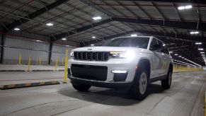 A white 2021 Jeep Grand Cherokee driving inside of a metal hanger building with a concrete floor.
