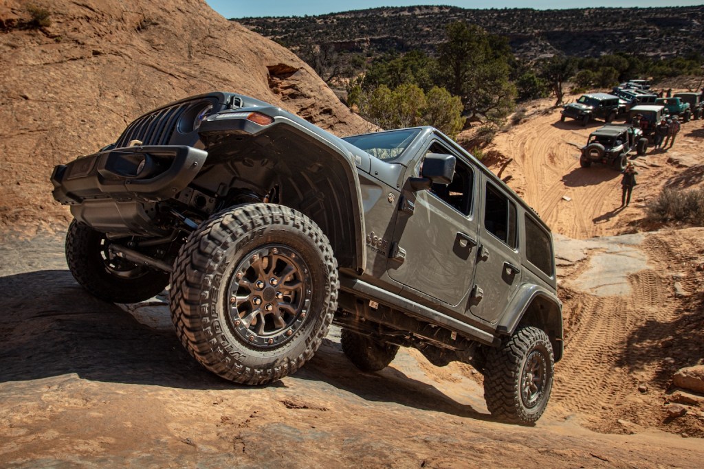 A grey 2021 Jeep® Wrangler Rubicon 392 climbing up a sandy hill