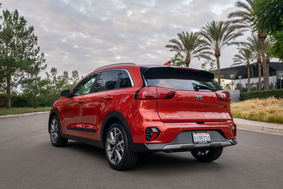 A red 2021 Kia Niro Touring model parked on an asphalt road near palm trees