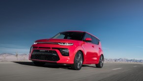 A red 2021 Kia Soul driving down an empty road