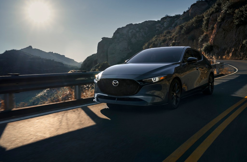 A dark blue 2021 MAZDA3 driving, the new Mazda3 is the best affordable AWD car on U.S. News' list