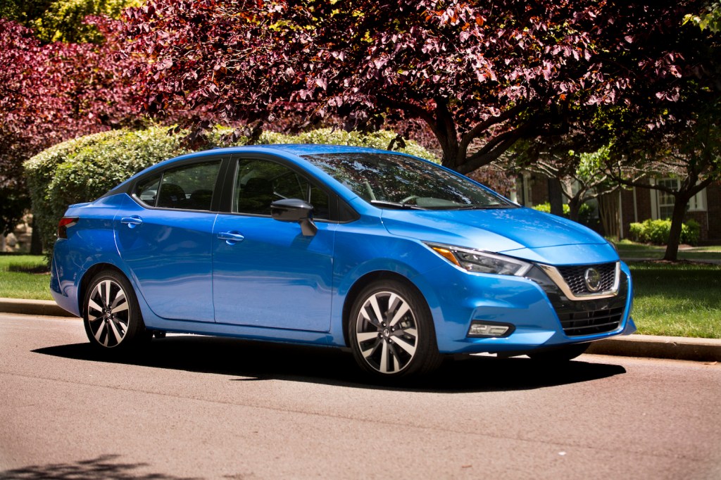 A blue 2021 Nissan Versa parked by flowers