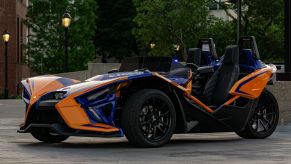 The front 3/4 view of an orange-and-blue 2021 Polaris Slingshot R in a parking lot