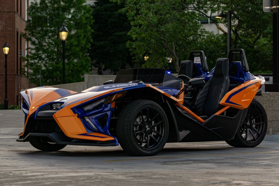 The front 3/4 view of an orange-and-blue 2021 Polaris Slingshot R in a parking lot
