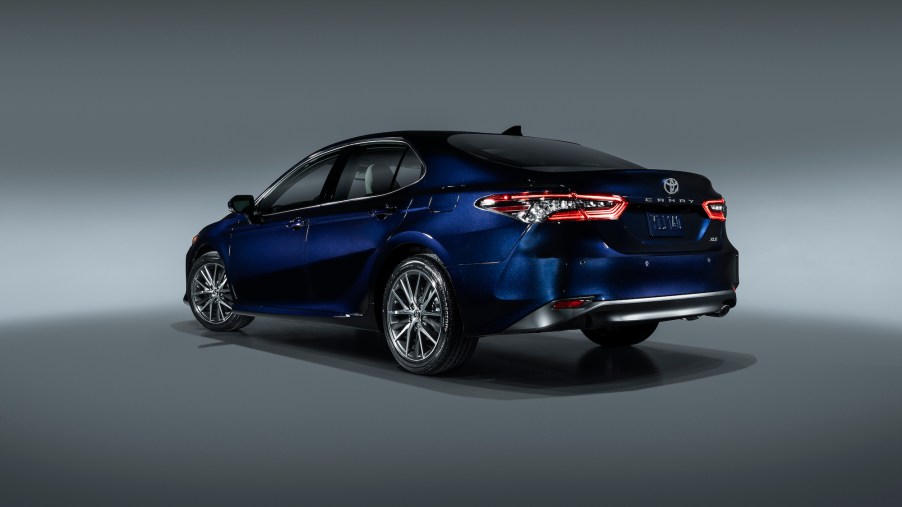 A deep-blue metallic 2021 Toyota Camry midsize sedan parked in a studio with a gray backdrop