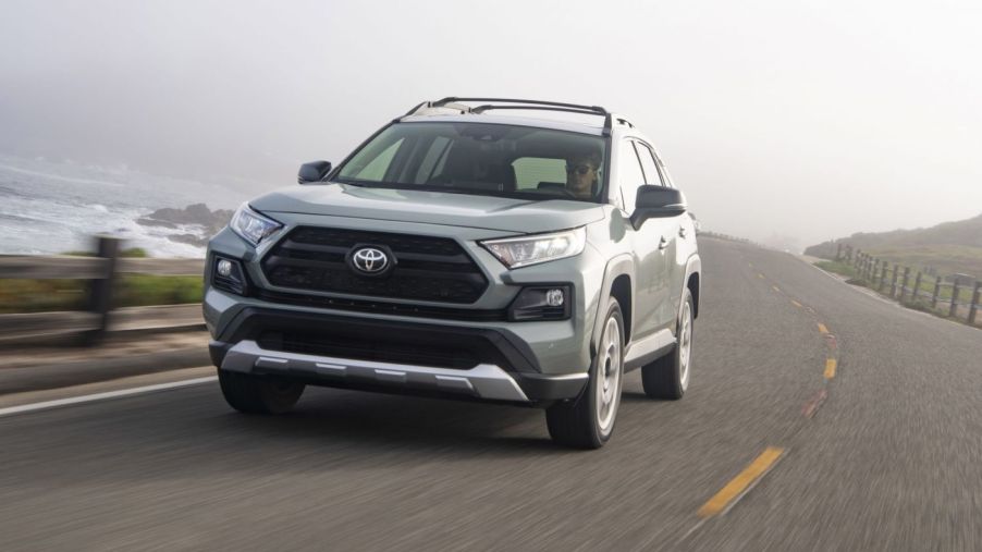 A silver 2021 Toyota RAV4 driving on a highway next to the ocean.