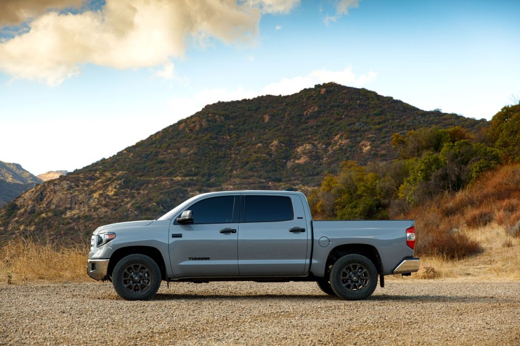 A 2021 Toyota Tundra Trail Edition gray pickup truck model parked on a dirt road near a grassy mountain