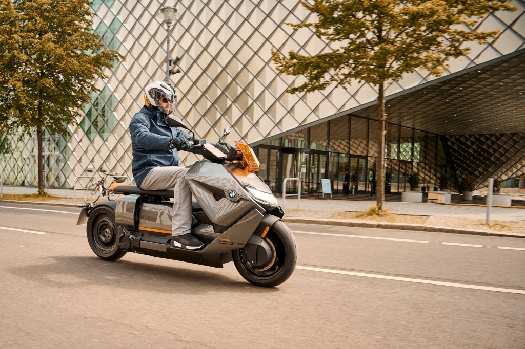 A blue-and-gray-clad rider on a gray-and-orange 2022 BMW CE 04 on a city street