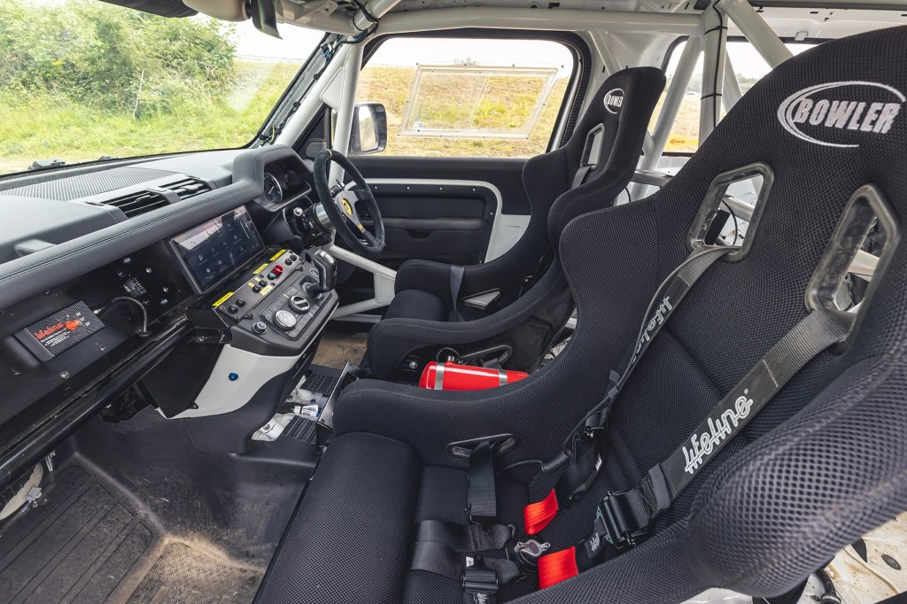 The racing seats, roll cage, and dashboard of a 2022 Bowler Land Rover Defender 90 Challenge