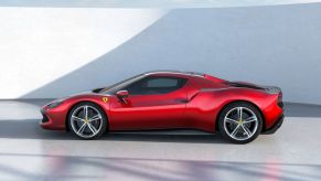 A red 2022 Ferrari 296 GTB sports car parked on a white floor in front of a white wall