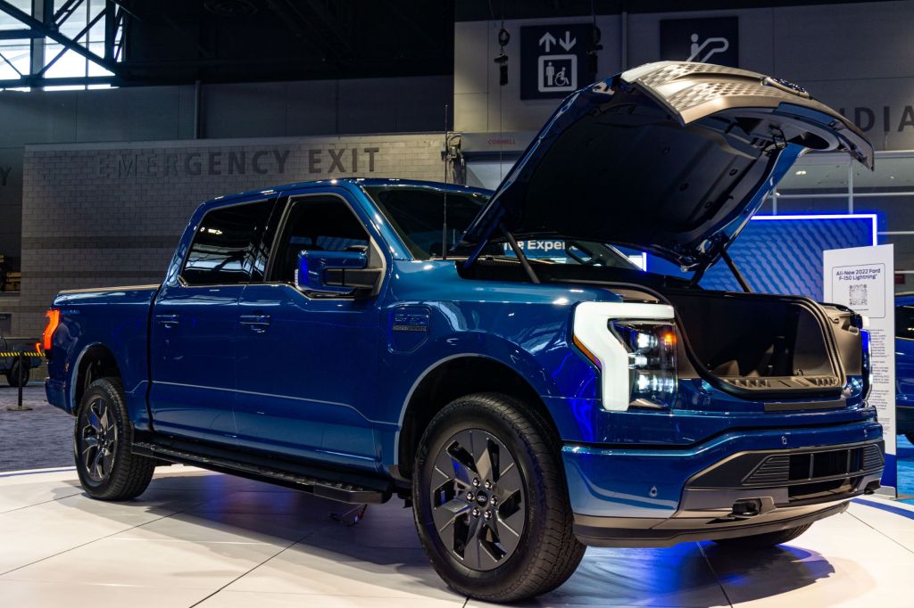 A blue 2022 Ford F-150 Lightning front 3/4 with open frunk at the 2021 Chicago Auto Show